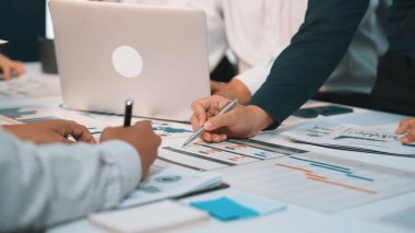 Dinamik bir iş ekibi bir strateji toplantısı sırasında işbirliği yaparak, dizüstü bilgisayarlardan faydalanıyor ve gelecekteki projeleri planlamak ve üretkenliği artırmak için finansal şemaları analiz ediyor. SACTR