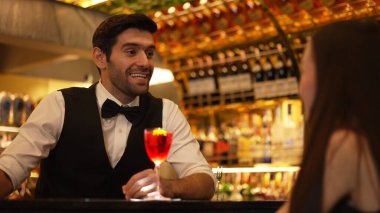 Barmen lüks tezgah barında güzel misafirler için çiçeklerle süslenmiş karışık votka kokteyli servis ediyor. Mükemmel canlı renk sunumu. Atmosfer gece kulübünü ön plana çıkarıyor. Vinosity.