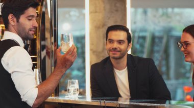 Güler yüzlü, VIP müşterileri içki tezgahında oturup barmenle konuştukları için davet eden ve ilk izlenimlerini harika yapan hoş geldin içkisi profesyonelliği hazırlayan çift. Vinosity.