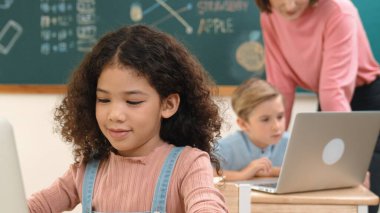 Çekici kız kodlama hızlı BTMM sınıfında kameraya bakarken mutlu öğretmen akıllı çocuk yazılım programını kontrol ediyor. Programlama kodu ve bilgisayar sistemi üzerine çeşitli öğrenci çalışmaları. Pedagoji.