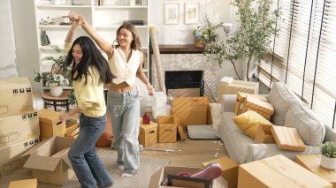 Taşınırken oturma odasında mutlu lezbiyen aşıklar dans ediyor. Birkaç arkadaş müzik eşliğinde salonda karton kutularla dans ederek serbest dans ediyorlar. Yeniden yerleştirme. Myrmidon.