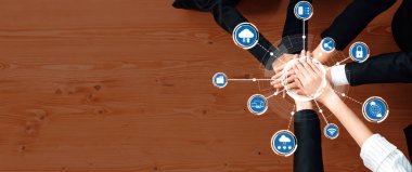 Çeşitli bir ekip, dijital bağlantıyı ve modern zorluklar için yenilikçi çözümleri sembolize eden teknoloji simgeleriyle çevrili işbirlikçi bir hesaplama çabası içinde ellerini birleştiriyor. Dostluk