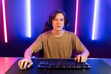 Kazanmak için çevrimiçi oyun oynayan akıllı flama makinesinin sunucu kanalı, neon ışıklı odada seçilen takım yarışması için izleyicilerle birlikte canlı yayında canlı yayında kulaklık takıyor. Bireysel.