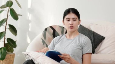 Kanepede oturan bir kadın ders kitabı okuyarak sosyal ve mesleki teknoloji bilgisini artırır ya da akıllı bir anne olmak için çocuk yetiştirir. Hayat boyu öğrenme konsepti. Uyumsuzluk.