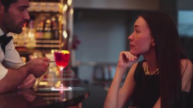 Barmen lüks tezgah barında güzel misafirler için çiçeklerle süslenmiş karışık votka kokteyli servis ediyor. Mükemmel canlı renk sunumu. Atmosfer gece kulübünü ön plana çıkarıyor. Vinosity.