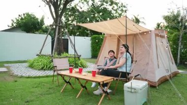 Aile hep birlikte bahçedeki kampta oturup yemek yiyor. Ebeveynler, genç nesil arasında iletişim kurmak ve zaman geçirmek için açık hava kamp faaliyetlerini kullanıyorlar. Uyumsuzluk.