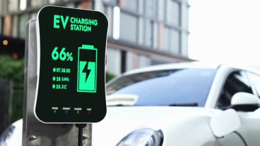Yerleşim alanındaki akıllı EV şarj istasyonunun gelecekteki temiz enerji kullanımı elektrikli araba aküsünü şarj ediyor. Modern şehir yaşam tarzında yüksek teknolojili EV arabaların teknolojik gelişimi. İnceleyin