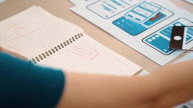 Mobil uygulama için kullanıcı arayüzü prototipi ya da masadaki program modeliyle birlikte web sitesi planlaması yapan bir şirket çalışanı. UX UI tasarımcısı kullanıcı dostu arayüz planını dikkate alır. Sinerjik