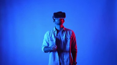 Sanal gerçeklik gözlüğünü açıp hologramı araklayan sıradan giysili profesyonel bir iş adamı. Üstveriye erişip girerken mavi arka planda duran yetenekli erkek model. Teknoloji. Aygıt.