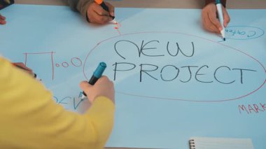 Yeni bir proje için yapılan beyin fırtınası oturumuna aktif olarak katılan canlı bir sahne. Kağıt vurgulama takımının işbirliği ve yaratıcılığı üzerine çeşitli renklerde işaretler. SACTR