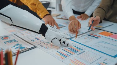 İnsan ve robot ellerin modern ofis ortamında iş haritalarını ve verileri analiz ederek yenilikleri ve takım çalışmalarını ön plana çıkaran işbirlikçi bir sahne.