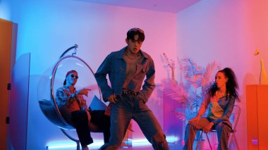 Çok kültürlü bir arkadaş kürsüde otururken Asyalı yetenekli bir dansçı modern müziğe geçiyor. Profesyonel dansçı, hipster takımı tezahürat yaparken ve desteklerken enerjik adımlar atıyor. Mutluluk.