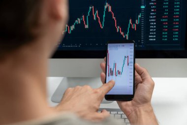 Akıllı borsa yatırımcıları ekranda akıllı telefon ile piyasa borsasını işaret ederek dizüstü bilgisayarın yanı sıra en yüksek dinamik yatırım oranını göstererek, modern işyerindeki veri planlamasına odaklanıyorlar. Bireysel.