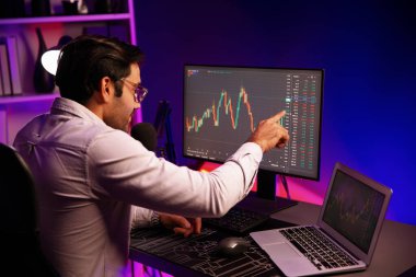 Akıllı tüccar işadamı, karanlık oda gecesinde neon ışıklı ofisteki arama pazarında yüksek kârla ekranda bilgisayar ve bilgisayar üzerinde dinamik borsa yatırımları üzerinde yoğunlaşıyor. Tahmin et..