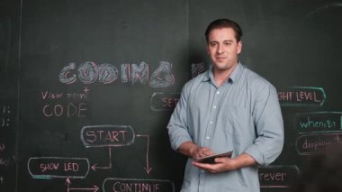 Kodlama programıyla ilgili öğrenci sorusuna beyaz öğretmen cevap veriyor. Beyaz kız, STEM teknoloji sınıfında dizüstü bilgisayar ekranı görüntülerken soru sormak, oy vermek, gönüllü olmak için elini kaldırdı. Öğretim