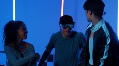 Gündelik gömlekli, gözlüklü, neon ışıkla dans eden farklı insanlar. Gece kulübünde dans ederken kameraya bakıp sokak dansı yapan çok kültürlü break dansçı. Mutluluk.