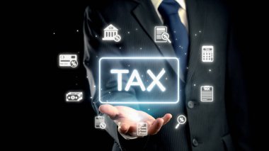 Resmi takım elbiseli bir işadamı, çeşitli mali simgelerle çevrili, dijital ve profesyonel bir ortamda modern vergilendirme kavramlarını gösteren parlak bir vergi sembolü sunuyor. Dörtgen
