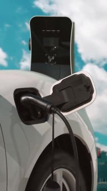 Elektrikli araç, EV araba şehir merkezindeki şarj istasyonunda şarj oluyor. Etrafı yüksek gökdelenlerle çevrili. Çevre dostu yenilikçi temiz enerji kavramı.