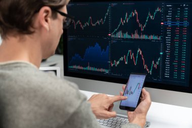 Akıllı borsa yatırımcıları ekranda akıllı telefon ile piyasa borsasını işaret ederek dizüstü bilgisayarın yanı sıra en yüksek dinamik yatırım oranını göstererek, modern işyerindeki veri planlamasına odaklanıyorlar. Bireysel.