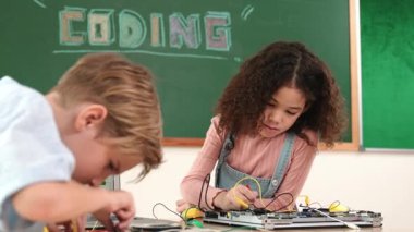 Dizüstü bilgisayar ekranında çalışan çeşitli öğrenci kodlama mühendisliği komut yazılımı ve yapay zeka programlaması yapıyor. Amerikalı kız, erkek makine tamir ederken ekipmanları teftiş ediyor. Pedagoji.