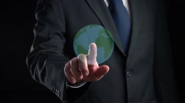 Takım elbiseli profesyonel bir adam, ekolojiyle ilgili dijital grafikler gösteren, yenilenebilir enerji kaynakları ve sürdürülebilir uygulamaları vurgulayan karanlık bir arkaplana karşı duruyor. Dörtgen