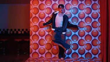 Asyalı break dansçı serbest stile geçiyor ve balon arka planlı kameraya bakıyor. Profesyonel hippi gündelik kıyafet giyer ve gözlük takar. Mutluluk.