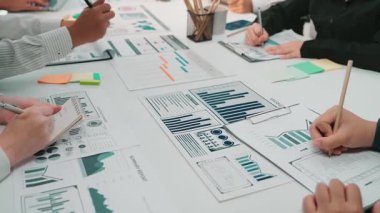 Bir konferans masası üzerinde dosya ve raporları analiz eden ve işbirliği ve stratejiyi vurgulayan çeşitli profesyonellerin yer aldığı dinamik bir iş toplantısı senaryosu. SACTR