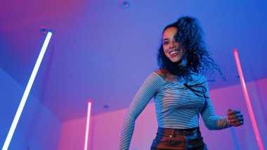 Latin dansçıların kameraya bakıp şehrin pop müziğiyle dans ettiği düşük açılı kamera. Profesyonel çekici hipster, mor veya neon ışıklı hip hop şarkısına geçiyor. Şık bir kumaş. Mutluluk.