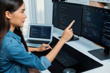 İnternet sitesinde kodlama programı uygulaması olan ve kot gömlek giyen bilgisayar hakkında bilgi veren IT geliştiricisi genç bir Asyalı kız. Güvenlik programlarıyla çevrili iki ekran. Taktik.