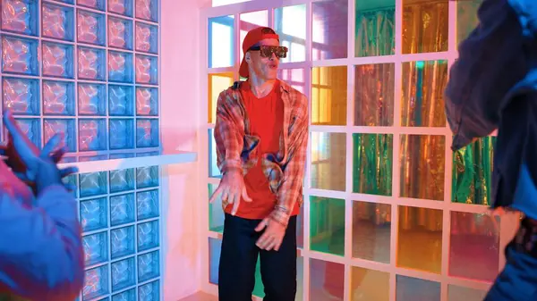 Kafkas dansçısı dans ederken çeşitli arkadaşları gece kulübünde neon ışıkta ayak seslerine bakıyor. Çoklu etnik kökenli hipsterin serbest stil müziğe geçişi ve mutlu bir adamın kameraya bakışıyla. Mutluluk.