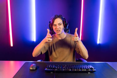 Kazanmak için çevrimiçi oyun oynayan akıllı flama makinesinin sunucu kanalı, neon ışıklı odada seçilen takım yarışması için izleyicilerle birlikte canlı yayında canlı yayında kulaklık takıyor. Bireysel.