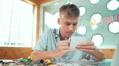 Zeki mutlu çocuk not alırken elektronik alet kullanmayı öğrenir ya da inceler. Lise öğrencisi STEM sınıfında otururken robotik makineleri tamir etmek için elektrikli aletler üzerinde çalışıyor. Öğretim