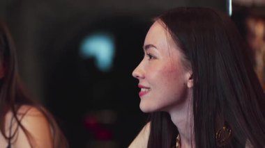 Lüks bir kokteyl barında grup arkadaşıyla konuşan güzel bir kadının portresi. Gece kulübünde sosyetik etkileşim için doğal yüz güzelliğini kostüm içinde yakalamak. Vinosity.