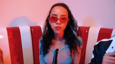 Mutlu kız kameraya bakıyor ve kanepede otururken pop müzik dinliyor. İspanyol kadın serbest stil dans ederken kameraya bakıyor neon ışıkta çeşitli arkadaşlarla dans ediyor. Mutluluk.