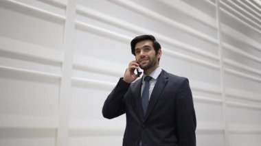 Yetenekli yönetici, iş arkadaşıyla proje hakkında konuşmak için telefon görüşmesi yapıyor. Yakışıklı erkek lider, ayakta durup kameraya bakarken satış hakkında konuşmak ve rapor vermek için iş ekibini arıyor. Sevinçli..