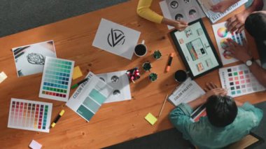 Proje yöneticisi renk paletleri seçerken tasarımcının tablete baktığı yukarıdan aşağıya hava görüntüsü. Profesyonel grafik tasarımının en üst görüntüsü ve logoya bakın. Yetenekli ekip grafikleri seçiyor. Sempozyum.