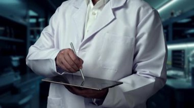 Stylus kalemle laboratuvarda yüzen tıbbi çapraz hologramı işaret ederken, doktorun tableti tutuş şeklini kapat. Pratisyen hekim teknolojiyi kullanarak ikonu kontrol ediyor ve bakıyor. İyileştirici.