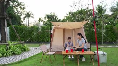 Aile hep birlikte bahçedeki kampta oturup yemek yiyor. Ebeveynler, genç nesil arasında iletişim kurmak ve zaman geçirmek için açık hava kamp faaliyetlerini kullanıyorlar. Uyumsuzluk.