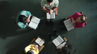 Yetenekli çeşitli duaların el ele tutuşması ve daireler çizerek Tanrı 'ya dua edişinin üst görüntüsü. Kucaklarda açık incille otururken el ele tutuşan insanların yukarıdan aşağı hava görüntüsü. Sempozyum.