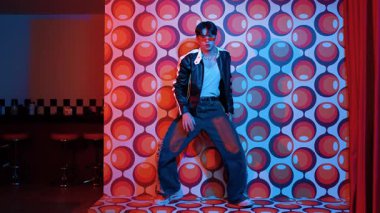 Asyalı break dansçı serbest stile geçiyor ve balon arka planlı kameraya bakıyor. Profesyonel hippi gündelik kıyafet giyer ve gözlük takar. Mutluluk.