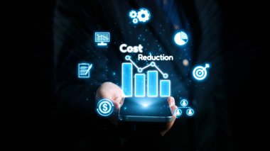 Parlak bir maliyet düşüşü grafiği gösteren akıllı telefonu tutan yakın plan bir el. Tasarımda veri ve analizlerin vurgulandığı bar çizelgeleri ve iş simgeleri yer alıyor. Dörtgen