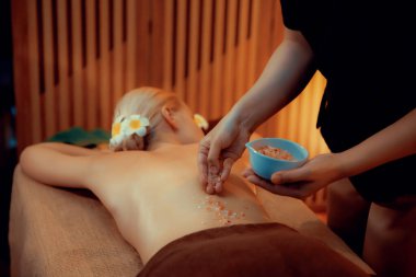 Lüks spa salonlarında sıcak mum ışığında cilt bakımı yaptıran kadın müşteri. Sağlık Spa vücut fırçasında tuz temizleme güzellik tedavisi. Sessiz.