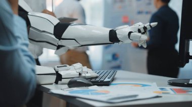 Robot bir kol dijital ekrana doğru uzanıyor ve modern bir ofisteki son teknolojiyi vurguluyor. Bu görüntü yeniliğin ve otomatikleşmenin özünü yakalar. Noogenesis