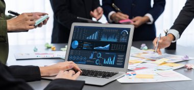 Analizci ekibi yaratıcı ve analitik beyin fırtınası fikri için bilgisayar ekranında BI veri paneli olan yapışkan bir not kullanıyor. Pazarlama stratejisi için finansal veri görselleştirme teknolojisini analiz et. Dahi.