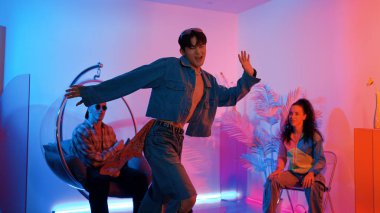 Çok kültürlü bir arkadaş kürsüde otururken Asyalı yetenekli bir dansçı modern müziğe geçiyor. Profesyonel dansçı, hipster takımı tezahürat yaparken ve desteklerken enerjik adımlar atıyor. Mutluluk.