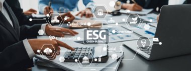 Modern ofis ortamında çevre, sosyal ve yönetim faktörlerini temsil eden grafikler ve simgelerle ESG uygulamaları yapan iş adamlarının elleri...