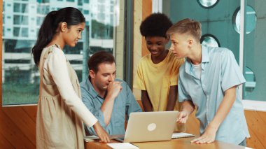 Öğretmen dizüstü bilgisayara bakarken liseli çocuk proje sunuyor. Çeşitli öğrencilerden oluşan bir grup ayakta duruyor ve planı açıklarken akıllı eğitmen de dinliyor ve tavsiye veriyor. Takım çalışması konsepti. Öğretim.