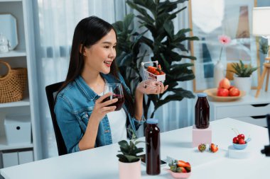 Gülümseyen, güzel Asyalı genç, lezzetli karışık çilek ve kiraz suyu detoksu içeceklerini inceleyen, sosyal medyada özel promosyon satışı için sağlıklı ürünler sergileyen. Taktik.