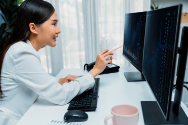 Modern ofisteki borsa grafiğinin kârını analiz etmek için bilgisayara bakan genç ve güzel Asyalı bir iş kadını. Finans sektöründe refah güvenliğine yüksek kâr yatırımı kavramı. Taktik.