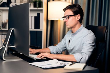 Akıllı iş adamı iş paragrafı dinamik pazarlama analizi planını analiz ediyor. Kağıt kağıtları ve bilgisayar monitörü raporlarını gece evdeki belge verileriyle karşılaştırmak için hazırlıyor. Bireysel.